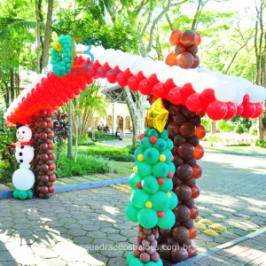 Decoração de Natal feita com balões, trata-se de uma entrada que simula uma casa decorada para as festas natalinas, confeccionada em balões marrons, brancos e vermelhos. Um boneco de balões simulando um boneco de neve e uma arvore de natal feita toda de balões verdes e marrons.