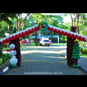 Decoração de Natal feita com balões, trata-se de uma entrada que simula uma casa decorada para as festas natalinas, confeccionada em balões marrons, brancos e vermelhos. Um boneco de balões simulando um boneco de neve e uma arvore de natal feita toda de balões verdes e marrons.