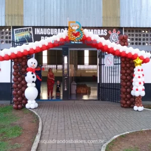 Decoração de Natal feita com balões, trata-se de uma entrada que simula uma casa decorada para as festas natalinas, confeccionada em balões marrons, brancos e vermelhos. Um boneco de balões simulando um boneco de neve e uma arvore de natal feita toda de balões brancos e marrons.